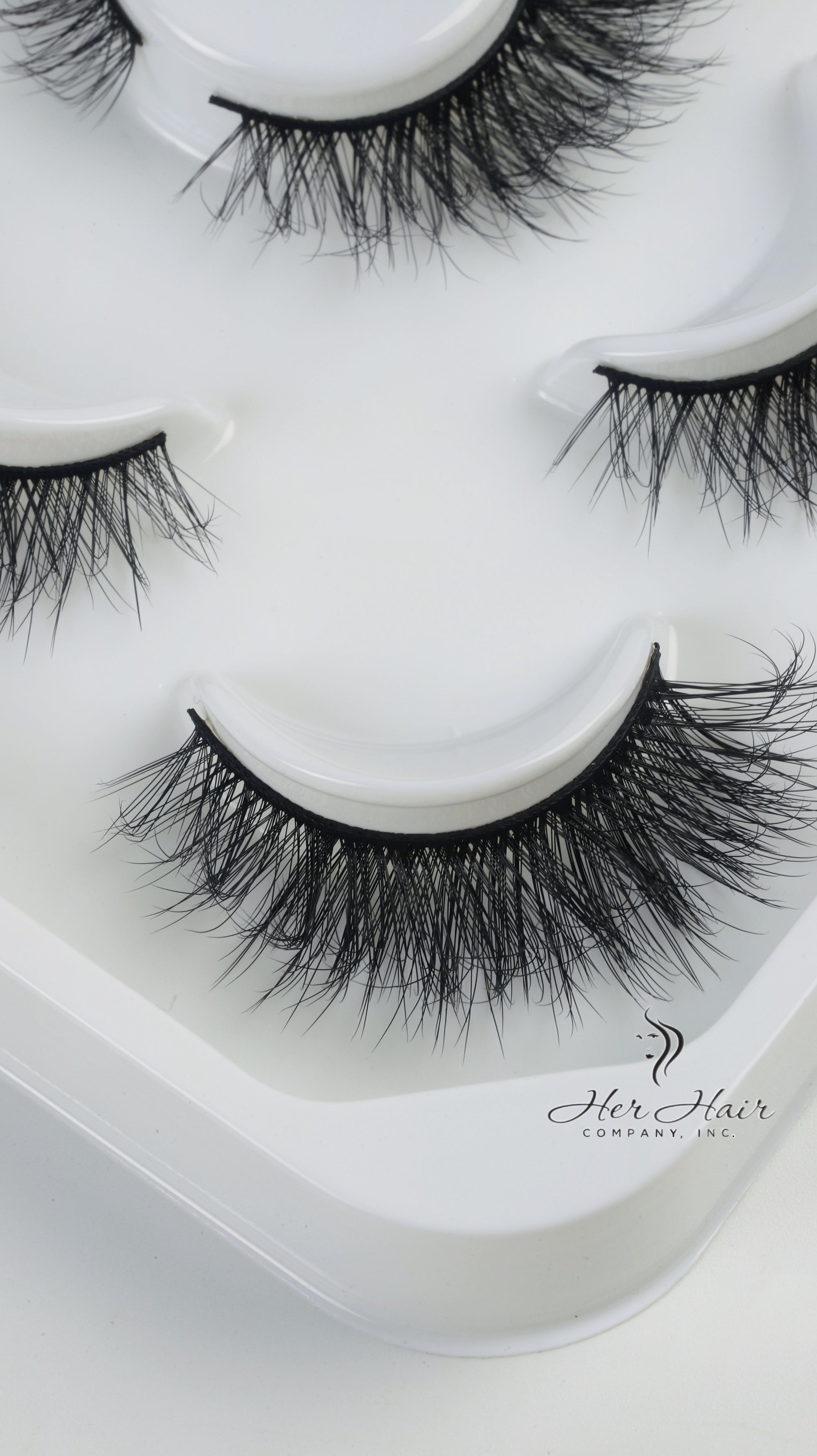Her Hair Company false eyelashes displayed on a clean surface, showcasing the natural lash style and length for enhanced eye beauty.