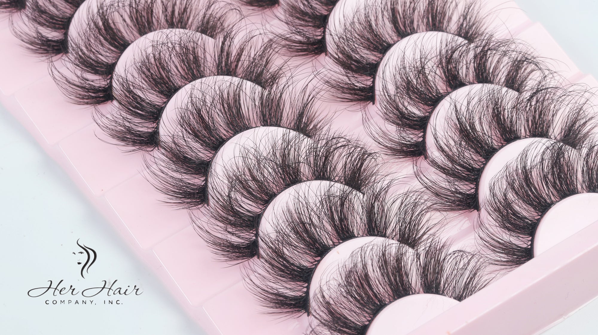 Close-up of Her Hair Company eyelash extensions showing individual synthetic lash strands on a white background.